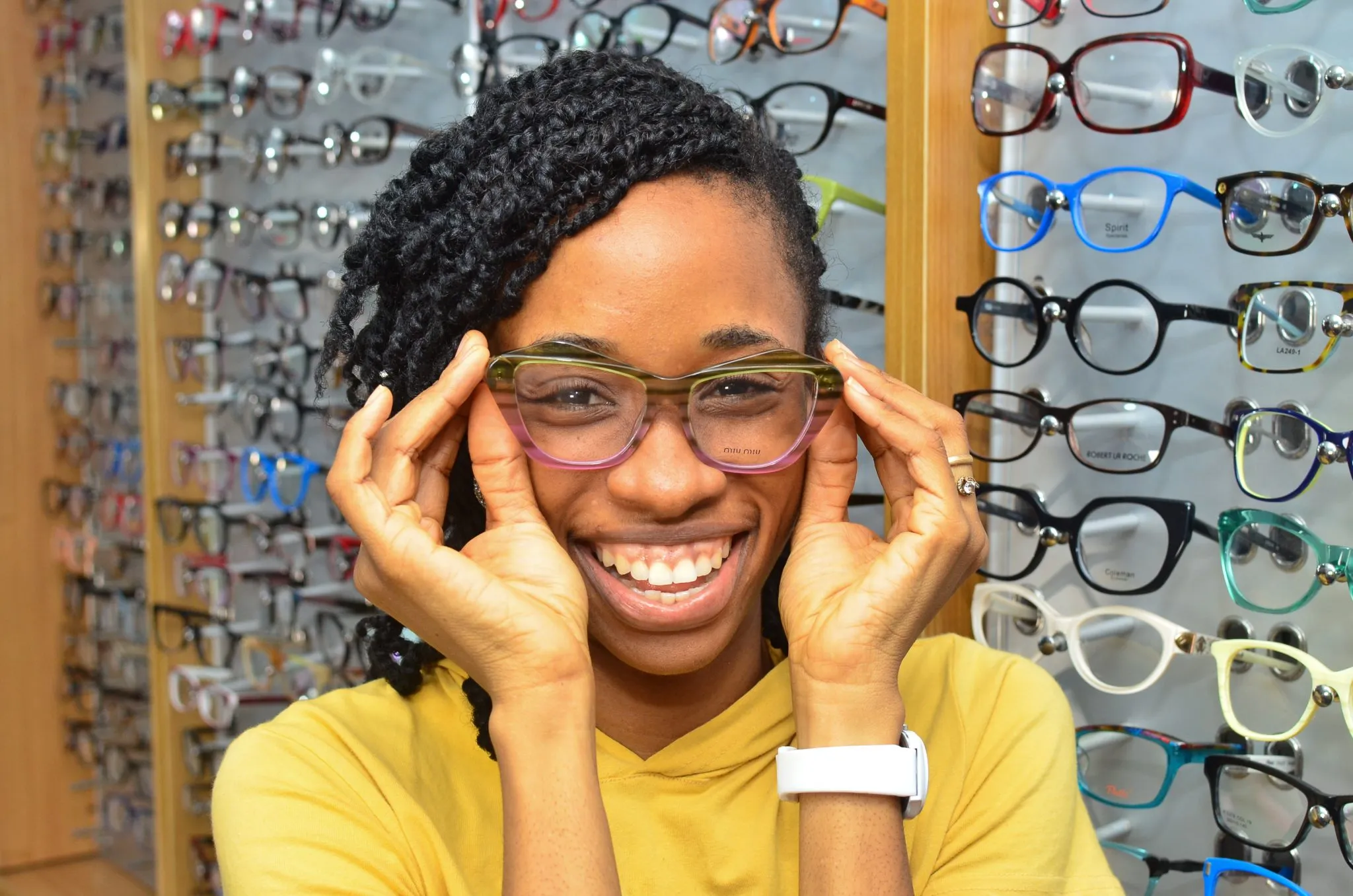 A smiling patient trying on new glasses frames at Locus Eye Clinic